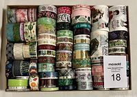 Photo of 78 assorted rolls of decorative washi tape showing many themes and colors packed tightly in a box.
