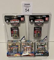 Six unopened Worlds Smallest Action Figures from Transformers, G.I. Joe, and Masters of the Universe, arranged in two rows in original packaging showing mini comic books.