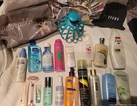 Lot of various used bath and body products including lotions, cleansers, creams, facial rollers, and cosmetic bags spread on a surface.