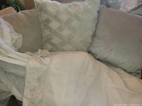 Photo showing three throw cushions and one draped curtain tasselled edge, illustrating fabric textures and colors.