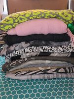 Stack of 12 folded shawls, scarves, and pashminas showing color and texture variety