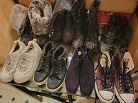 Photo showing eight pairs of ladies' footwear including boots and runners arranged together, showing styles and condition.