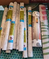 Photo of ten rolls of adhesive shelf and drawer liners with labels and a roll of Easyliner and floral liner