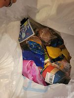Open plastic bag showing colorful party supplies including balloons and decorations.