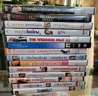 Photo showing stacked DVD cases of romantic comedy movies with titles visible on spines.