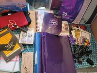 Photo showing multiple stationary supplies including pencils, scissors, notebooks, binder, mouse box, sticky notes and paper packs.