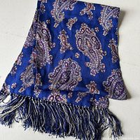 Full view of the folded silk scarf showing paisley pattern and hand-tied fringes.