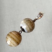 Frontal close-up photo of pendant showing two faceted agate balls connected vertically with a marked 925 sterling silver bail at top.