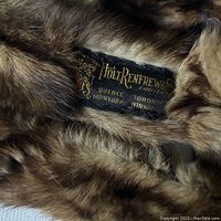 Close-up photo showing the black cloth label sewn onto the underside of the mink pelt with gold lettering for Holt Renfrew & Co Limited and locations including Quebec, Montreal, Toronto, Winnipeg.