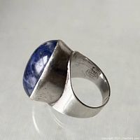 Angled side view of sterling silver ring with raised blue and white sodalite cabochon stone, showing band and bezel setting.