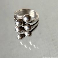 Front view of sterling silver folded hand ring showing stacked rounded silver elements on a split band.