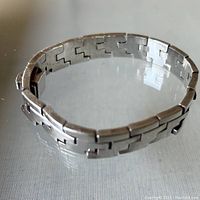 Side view of sterling silver hinged bracelet showing construction of linked hinged sections and clasp.