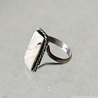 Side angled view showing twisted rope border and split shank band design of the sterling silver ring with rectangular abalone inset.