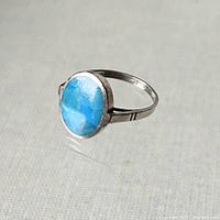Front view of delicate sterling silver ring with bright blue round turquoise stone, flat recessed set.