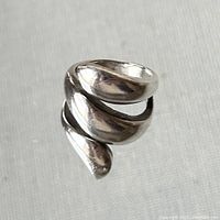 Close-up image of a polished sterling silver wrap ring marked 925, showing its shiny, smooth surface and curved coil design.