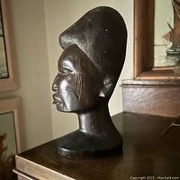 Side profile view of the carved ebony Makonde head bust showing the detailed tattoos on the face and textured hair.