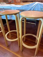 Two matching wooden barstools shown side by side, with round seats and four legs.