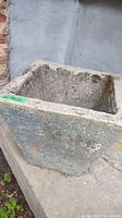 Square concrete garden pot with rough exterior and worn blue paint on sides