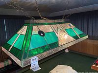 Full view of the stained glass pool table light fixture hanging over pool table. Shows overall shape, colors, and hanging chains.