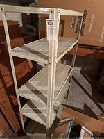 White metal shelving unit with four shelves shown from a frontal angle with surrounded basement items.