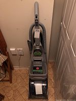 Full front view of Hoover Steam Vac carpet cleaner including attached hose, placed on tiled floor.