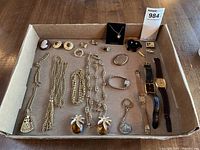 Full assortment of costume jewelry laid in a box including necklaces, watches, clip-on earrings, cameo brooch, rings, locket showing general condition and contents