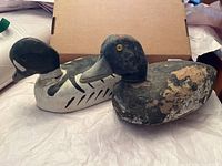 Pair of two wooden decoy ducks laying side by side, showing full bodies and overall condition.