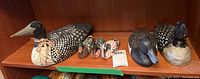 Photo showing all six duck decoys on wooden shelf, including three large decoys and three smaller miniatures.