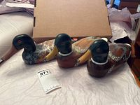 All three wooden decoy ducks displayed together, showing varied body colors and signs of wear
