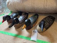 Four assorted wooden decoy ducks arranged on carpet, showing overall lot including varying shapes and sizes.