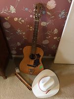 Lot overview showing guitar, recorder in case, and cowboy hat