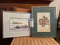 Both framed Indigenous prints side by side on a wicker surface, showing general presentation and framing.
