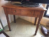 Front view of the solid wood occasional table showing overall structure, turned legs and drawer with two brass knobs.