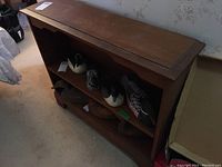 Full view of the small wooden bookshelf with a decorative scalloped edge on the inner frame, containing several wooden carved birds on the shelves.