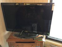 Front view of the Toshiba TV on a stand showing the screen and remote control resting on the table surface.