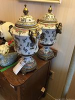 Front-angle view of both lidded porcelain urns on tabletop