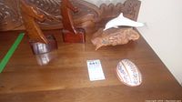 Top view of the wooden horsehead bookends, dolphin sculpture, tortoise art piece, and decorated oval-shaped object on a wooden table.