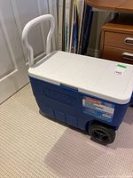 Full view of blue and white Coleman wheeled cooler with handle showing overall condition and design