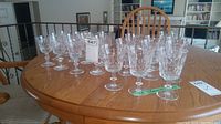 Photo showing full set of 22 crystal wine glasses arranged on wooden table, including both white and red wine glasses.