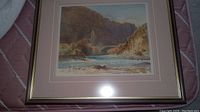 Framed landscape print showing cliffs, water, and sky.