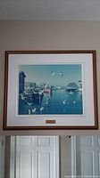 Full view of framed wall art showing harbor with boats and seagulls.