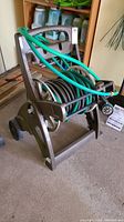 View of the hose reel cart with hoses coiled and green spray nozzle attached