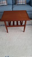 Front angle view of teak side table showing rectangular top and tapered legs with visible water stain on tabletop.