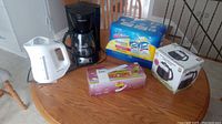 Photo showing black Black and Decker coffee maker, white electric kettle, six canisters Lysol wipes in blue packaging, Vidalia Chop Wizard dicer box and replacement coffee carafe.