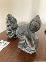 Front view of both soapstone carvings showing kneeling figure and seated figure with child