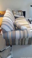 Side view of striped 2-seater La-Z-Boy sofa bed with cushions on carpeted floor.