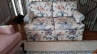 Front view of the floral two seater sofa showing seat cushions and arm covers.