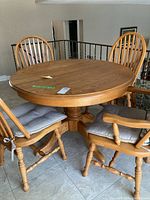 Full view of round oak table on pedestal base with four chairs around it