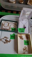 Six 10K gold necklaces displayed in trays (purple pendant, V-shaped, and four chains)