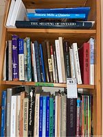 Three shelves filled with books focusing on Ontario historic mills, shaping of Ontario, Kingston history and regional topics.
